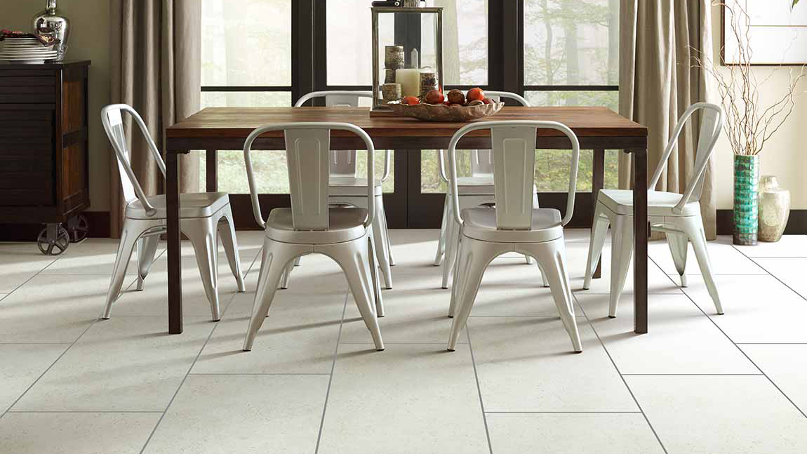 Brown dining table surrounded by modern white chairs and a white tile floor